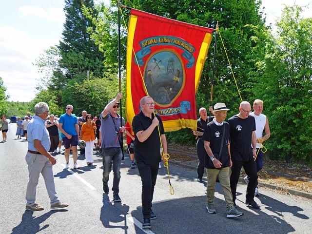 Former NUM members proudly carry a banner to the Arkwright memorial.