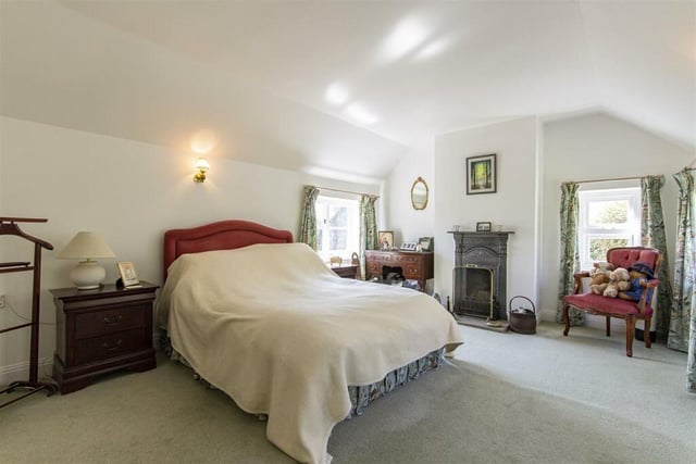 The master bedroom, one of four double rooms, has a cast iron fireplace with open grate sitting on a stone hearth.