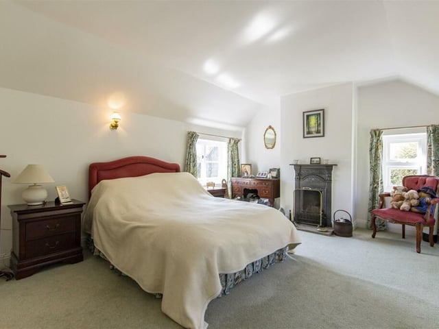 The master bedroom, one of four double rooms, has a cast iron fireplace with open grate sitting on a stone hearth.