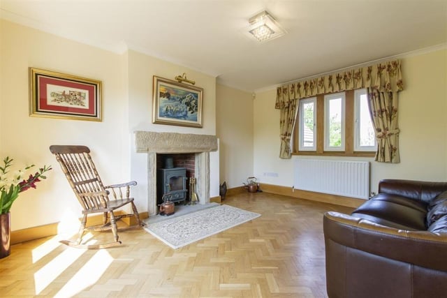 This generously sized reception room has a multi-fuel stove sitting in a stone fireplace.