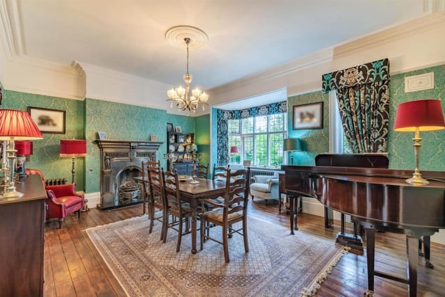 The dining room boasts an eye-catching fireplace and a high ceiling. There is a serving hatch leading to the kitchen.