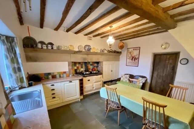 The kitchen is in keeping with the farmhouse, boasting exposed ceiling timbers and meat hooks, an oil-fired Aga housed in an original stone fireplace and slate tiled flooring.