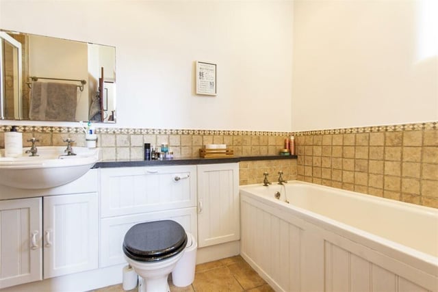 A four-piece suite comprises bath, shower cubicle with mixer shower, semi-recessed wash basin and wc.  The room is partially tiled and has a vintage style radiator.