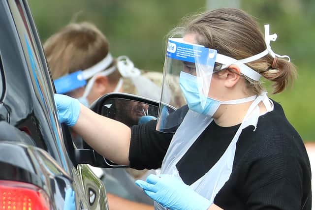 A medical worker wearing a protective face mask and screen, disposable gloves and a plastic apron, takes a swap at a coronavirus drive-through testing centre. (Photo by Warren Little/Getty Images)