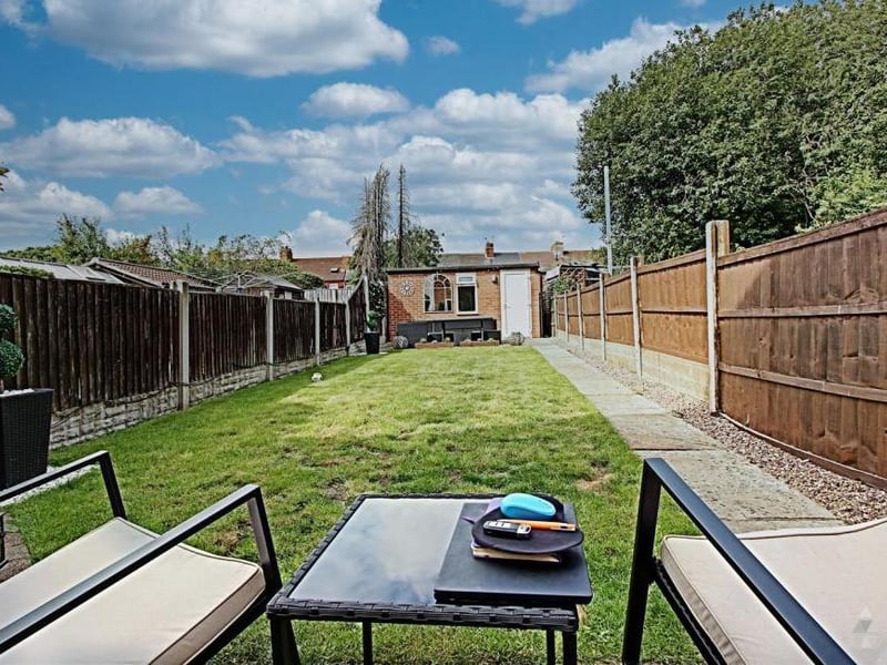 The long, enclosed garden at the back, which leads to the patio and bar. At the front, there is room for parking on the street.