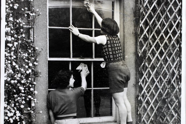 Girls from Sheffield Youth Hostel Association are pictured cleaning the windows of the new hostel, Leam Hall, which is situated between Hathersage and Eyam, for its official opening at Whitsuntide on May 17, 1939. The girls formed working parties with boys to prepare the new hostel - cleaning floors, making curtains, and arranging the furniture every evening. Mrs Rose-Innis, the owner of Leam Hall, generously loaned it to the YHA at a nominal rental.  (Photo by Harry Shepherd/Fox Photos/Hulton Archive/Getty Images)