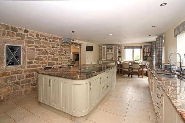 Shaker-style units set beneath a polished granite worksurface with matching upstand, a large island which creates a breakfast bar and an exposed stone wall with an inset wine rack are features of the dining kitchen.  Integral appliances include a 12-place setting dishwasher, two fridges, and eye-level steam oven, microwave oven and conventional oven. The dining area  has a fitted window seat and ample space for a family dining table.  There are views over the open countryside and fields at the rear of the property.