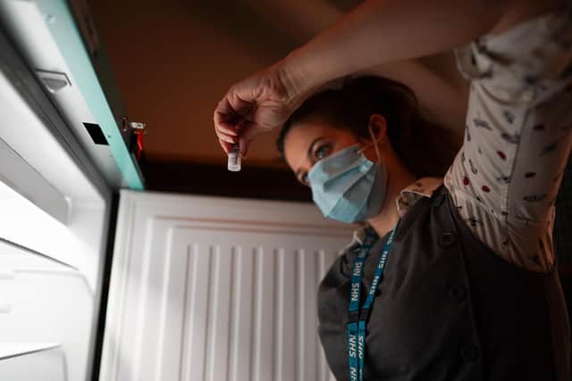 A pharmacist removes Pfizer BioNTech Covid-19 vaccines from a fridge. (Photo by Ian Forsyth - Pool/Getty Images)