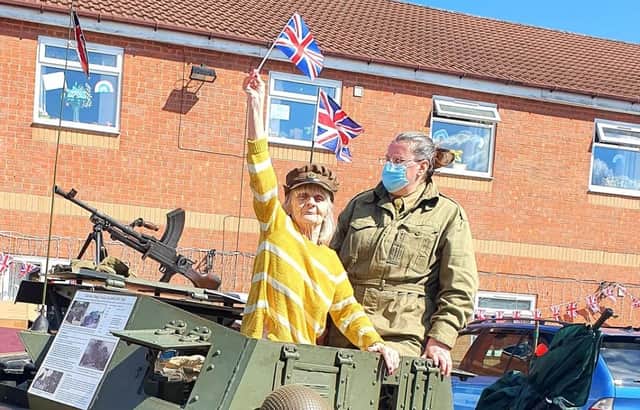 Jane Mosley, 77, waves the flag in the 'Dingo' Scout Car on its visit to Langdale Lodge Care Home in Chesterfield.
