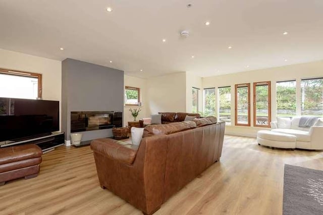 The bright living room has a modern fireplace and views out to the garden.