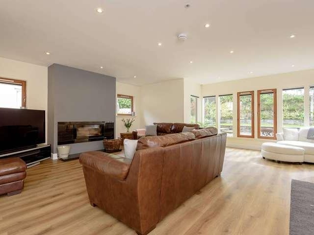 The bright living room has a modern fireplace and views out to the garden.