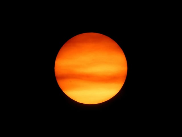 The sun sets behind smoke caused by local wildfires at Huntington Beach.