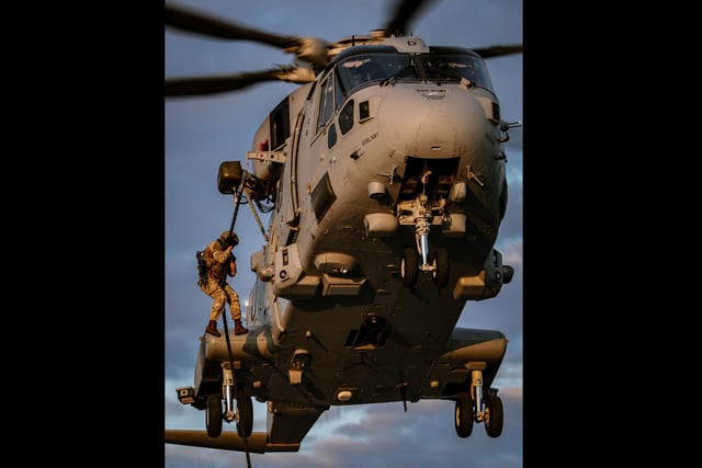 A Royal Marines Commando begins his descent from a Merlin helicopter during fast roping exercises on HMS Queen Elizabeth. This images was part of a winning selection for the Commandant General Royal Marines Prize won by HMS Queen Elizabeth. Picture by Leading Photographer Kyle Heller