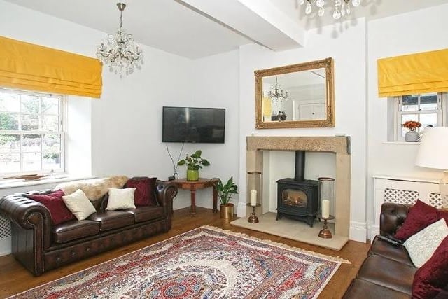 The drawing room has stone lintels and tiled hearth, housing a living flame gas stove. There are fitted cupboards providing shelving and storage space.