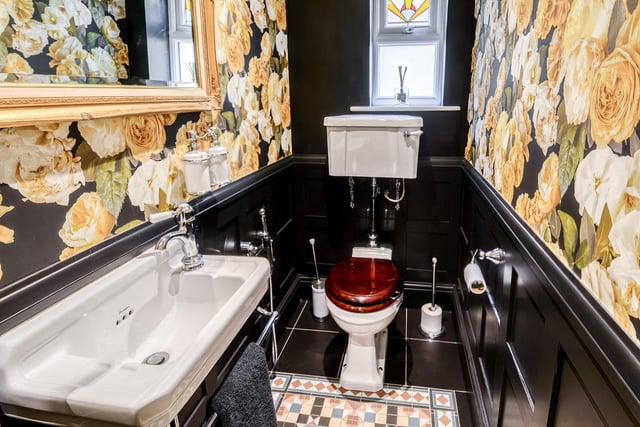This room, containing wash basin and wc, has partly wood panelled wall coverings, black tiled flooring and a period style radiator.