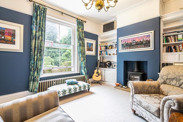 Here's the lounge - decorated in an on trend shade of blue with a large, light-giving window and a tasteful column radiator. The log-burning stove is a selling point.