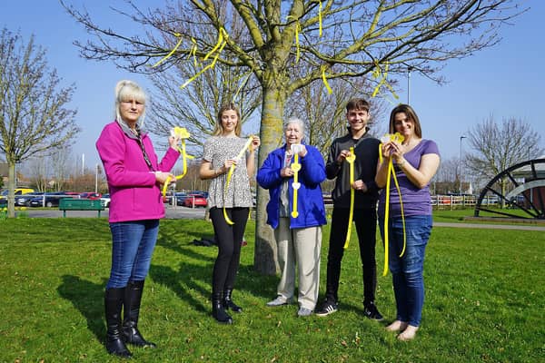 April Johnson, of the Community Unity Project, with Phoebe Mousley, Sandra Mousley, Oliver Mousley and Nicola Mousley dressed a tree with yellow hearts and ribbons at the Arc in Clowne to remember lives lost to Covid-19. Picture by Brian Eyre.