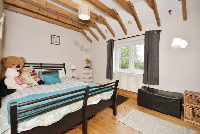 The second bedroom in the main residence has a vaulted ceiling and strippped wooden floor.