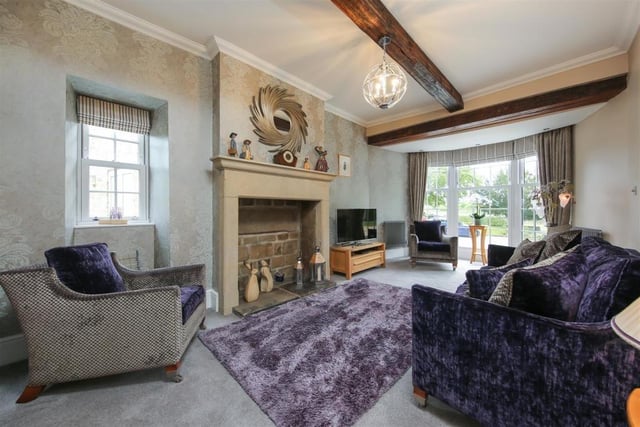 Ceiling beams, stone fireplace and bay-fronted window catch the eye in this cosy room.