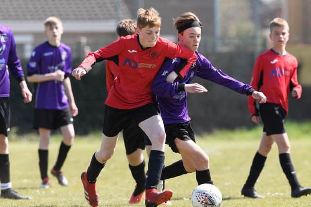 A Widbrook Hawks (red) player locked in battle with a Gosport Falcons Blue opponent for the ball in their Mid Solent Youth League under-15s match. Picture: Keith Woodland (240421-438)
