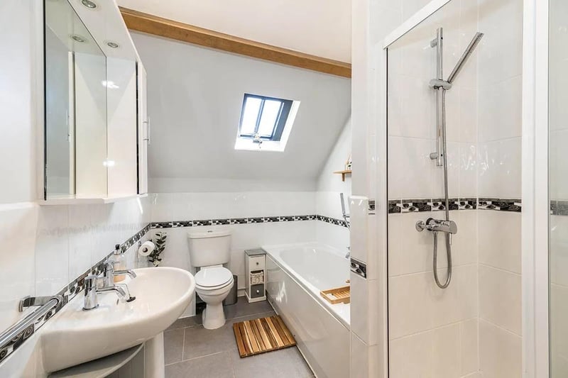 Delightful modern suite that comprises soak bath with central taps, double walk-in shower, low level WC, pedestal sink, fully tiled walls and floor, ceiling spot lights, exposed beams and wall-mounted radiator.