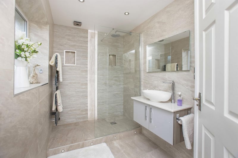 There is complimentary tiling to the walls and floor, inset ceiling spotlights and a wall-mounted towel rail.