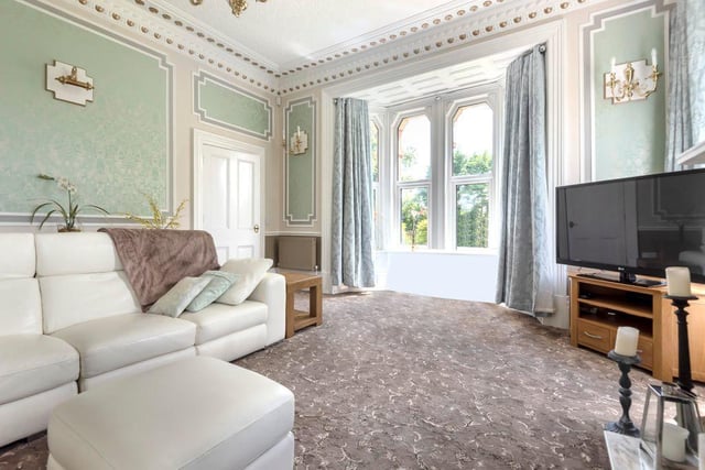 The house contains two living rooms,; this one has stunning period plaster work on the ceiling and walls and an eye-catching fireplace. A beautiful bay window bathes the room in natural light.