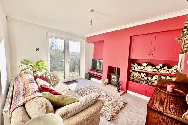 The family room has a multi-fuel stove set into the chimney breast, stereo/audio plinth to one alcove and built-in cupboards and shelving on the other side.