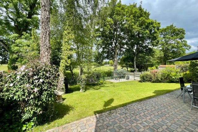 The garden contains a patio area for al fresco meals or drinks and a lawned area with rural views beyond.