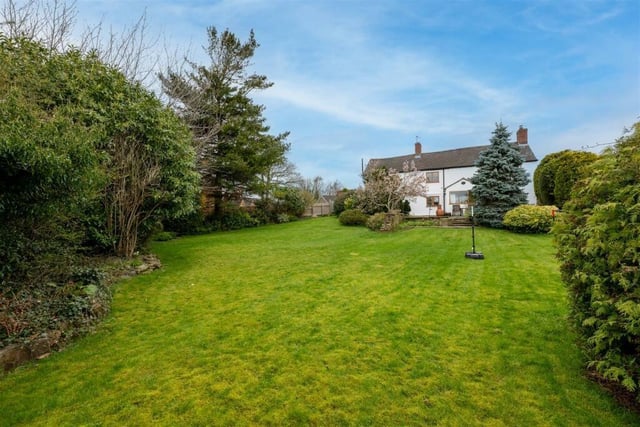There is a large stretch of grass in front of the house which has garden areas on three sides.