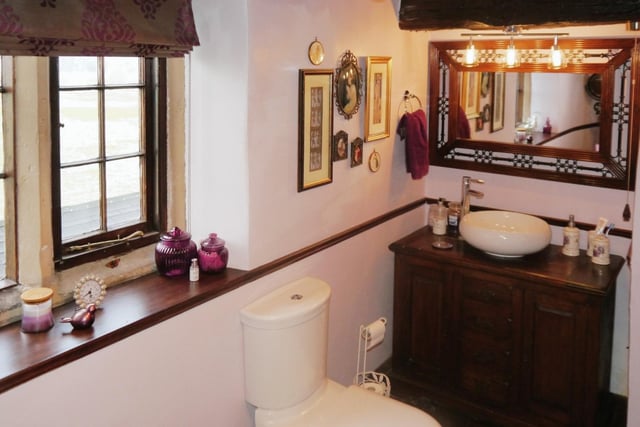 A cloakroom is fitted with a two-piece suite comprising a wash hand basin with cupboard under and low-level WC.