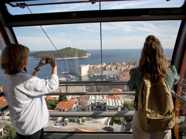 Tourists in a cable car are seen taking photos of the old town of Dubrovnik - flights to Dubrovnik and Pula can be booked from Doncaster Sheffield Airport.