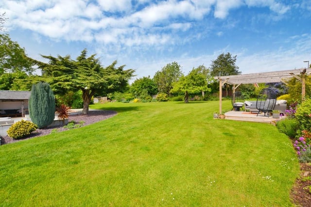 Stepping outside, let's take a look at a handful of exterior photos, starting with this large, formal lawned garden at the back of the house. It is totally enclosed with flower/shrub borders. You can also see decking with a seating area and pergola.