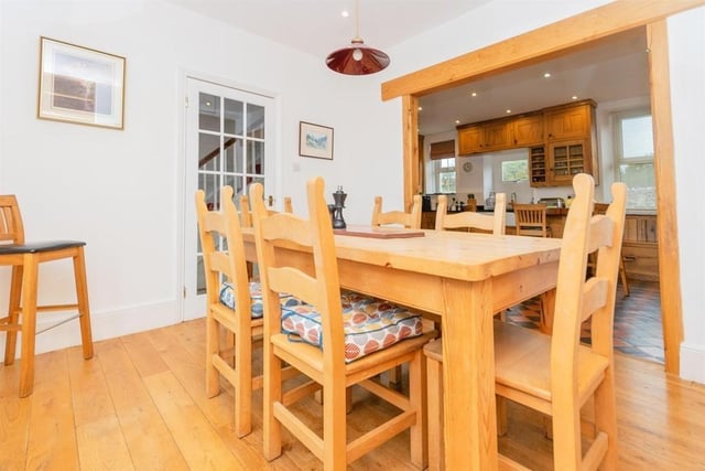 The dining room flows into the kitchen through a wooden archway. There is a fireplace, built-in storage in the alcoves and a window looking out over the garden.