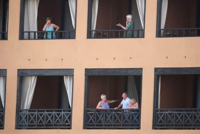 Tourists stand on the balconies of their rooms at the H10 Costa Adeje Palace Hotel in La Caleta, where hundreds of people were confined to their rooms after an Italian tourist was hospitalised with a suspected case of coronavirus. (Photo by DESIREE MARTIN / AFP)