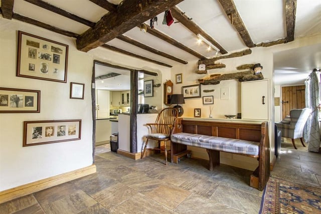 This view of the boot room shows the character of the cottage, from the exposed ceiling beams to the stone floor and the latch door beyond.