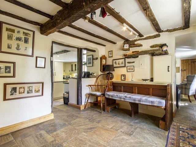 This view of the boot room shows the character of the cottage, from the exposed ceiling beams to the stone floor and the latch door beyond.