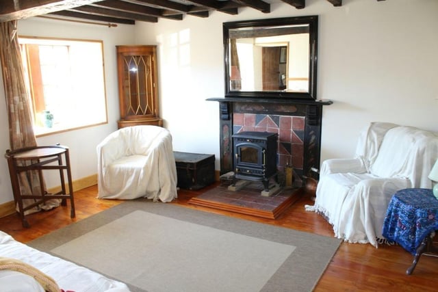 A wood burning stove sits on a quarry tiled hearth in the lounge where there are ornamental beams to the ceiling and a polished floor.