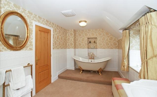 A free-standing bath set on lion's paw feet takes pride of place in this luxurious bathroom. There is a separate shower cubicle with mixer shower.
