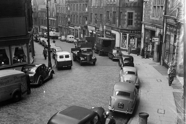 Traffic on Cockburn Street in 1960, with the Clinkscales Oswald & Sons shop front sign visible at top of Fleshmarket Close.