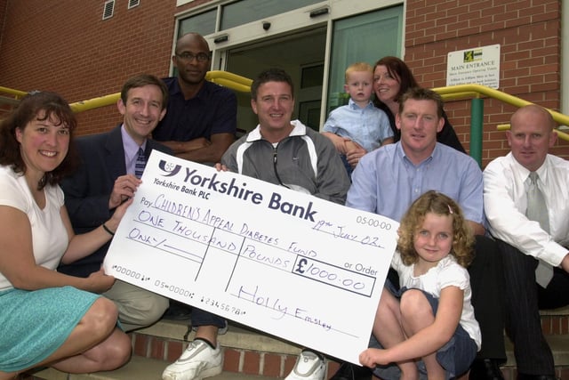Holly Emsley (right) pictured presenting a cheque for £1000 to  Dr Neil Wright, Consultant Endocrinologist, and Diabetes specialist nurse Nicola Rogers at the Sheffield Children's Hospital in 2002. Looking on are parents Andy and Michelle ,brother Benjamin and former sheffield footballers John Pearson,Kevin Gague and Tony Agana.