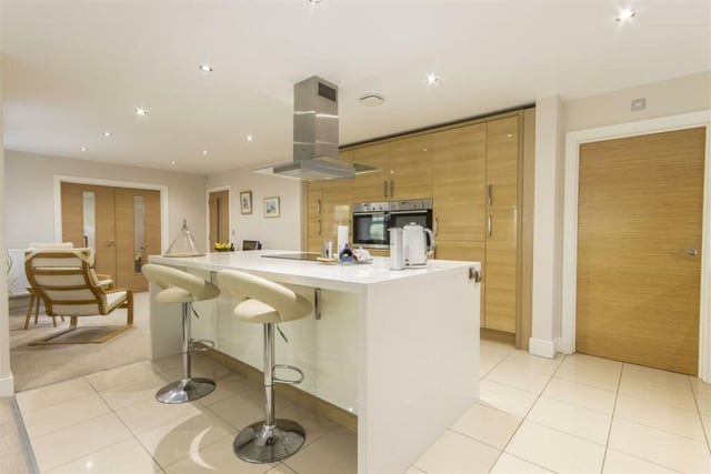 A fabulous open-plan, L-shaped kitchen boasts contemporary two tone hi-gloss wall, drawer and base units with under unit lighting and quartz work surfaces over, two pull out larder cupboards, an island unit and integrated appliances.