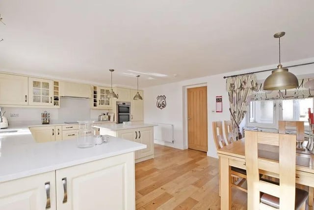 The superb dining kitchen has a range of cream base and wall units, an island, white quartz work surfaces and integrated appliances including a large fridge, double electric oven, induction hob with extractor fan above and a dishwasher.