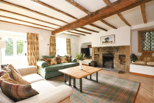 A stone fireplace and beams within this room that has doors out to the gardens.