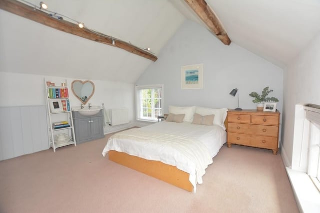 To see the remaining two double bedrooms, let's move up to the third floor. Bedroom number four has a vaulted beamed ceiling and also its own wash hand basin with vanity storage beneath. There are windows to the side and front of the property.
