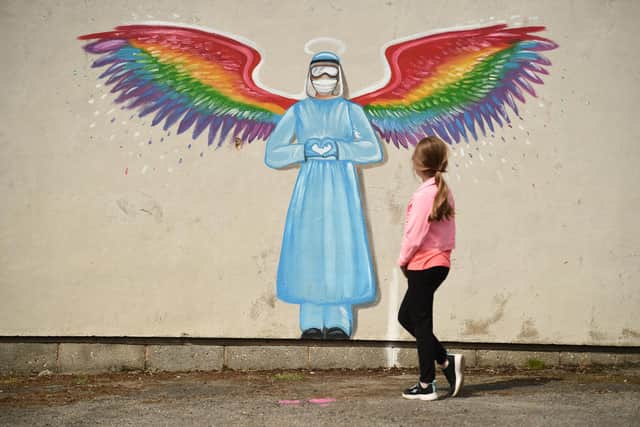 A girl looks at a mural by artist Rachel List paying tribute to NHS staff battling the COVID-19 outbreak  (Photo by OLI SCARFF/AFP via Getty Images)