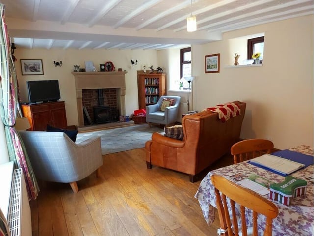 A log burner heats the living/dining room which has a beamed ceiling and solid wood flooring.