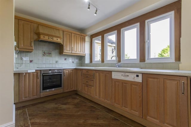 The kitchen has limed oak units with complementary work surfaces and integrated appliances including a dishwasher, electric oven hob with extractor hood.