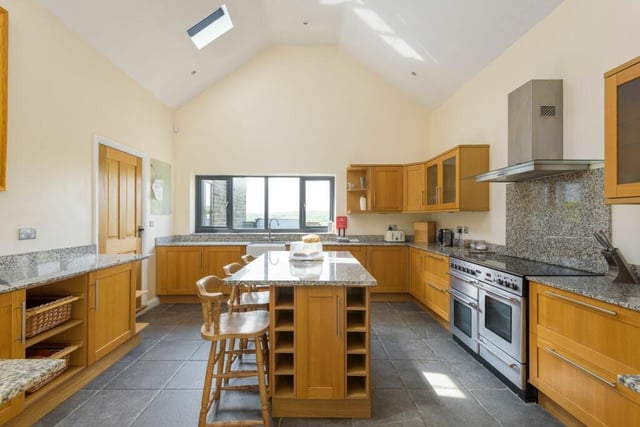 Enjoy a relaxed meal at the central island in this modern kitchen which is fitted with wall and base units,  granite worksurfaces and splashbacks and has a range-style cooker.