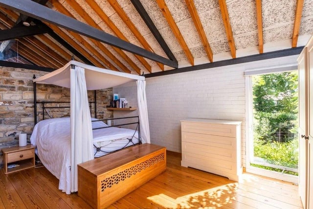 Wooden flooring and exposed beams create interest in this bedroom.